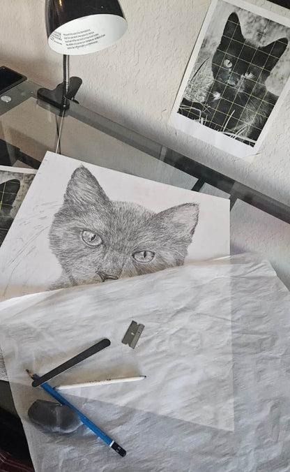 Artistic drawing of a cat on paper with a pen and eraser, surrounded by art supplies.