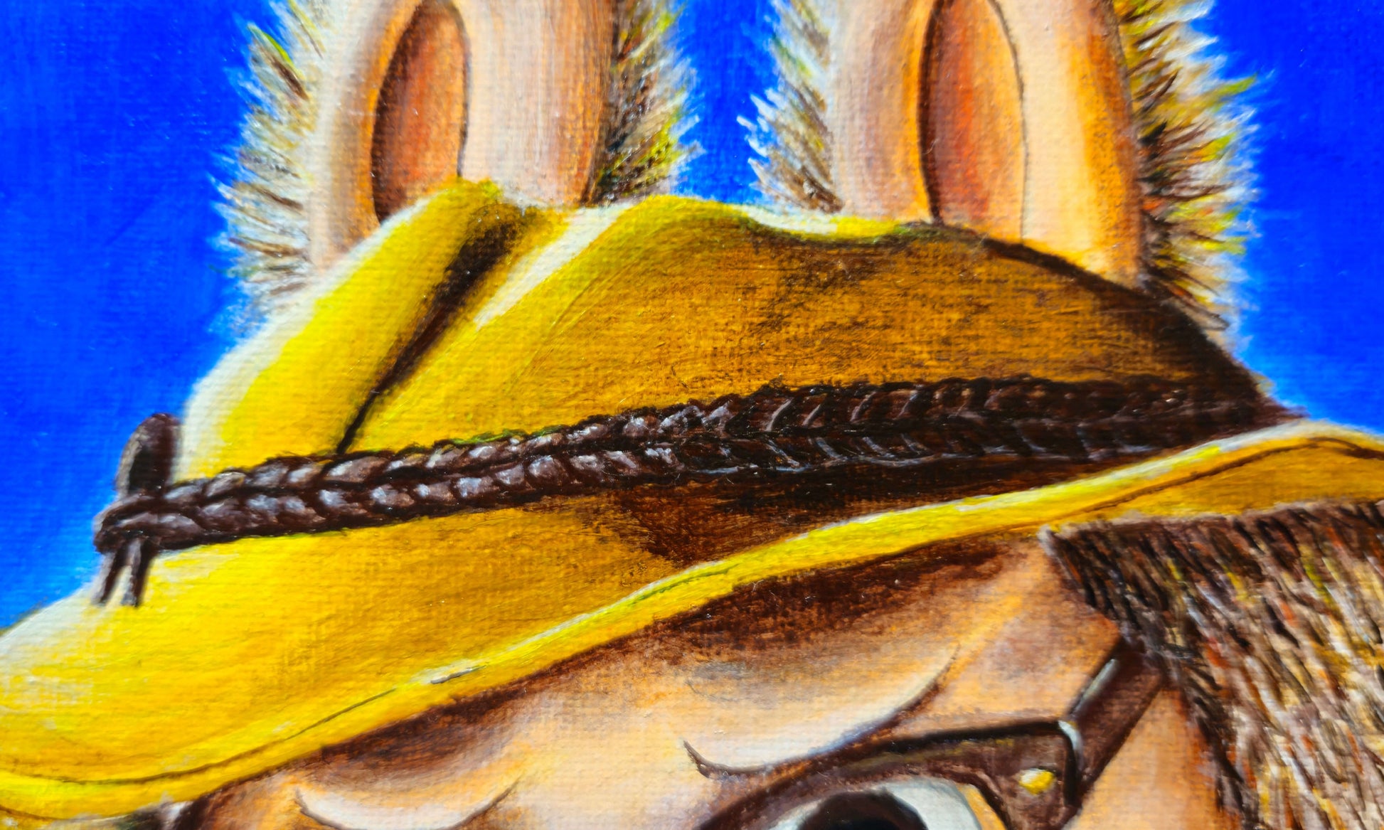 Close-up of Salary Daddy Labubu's gold fedora and brown furry ears against a blue background